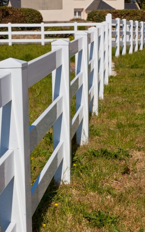 Country New White Plastic Fence after Mowing. Sunny day