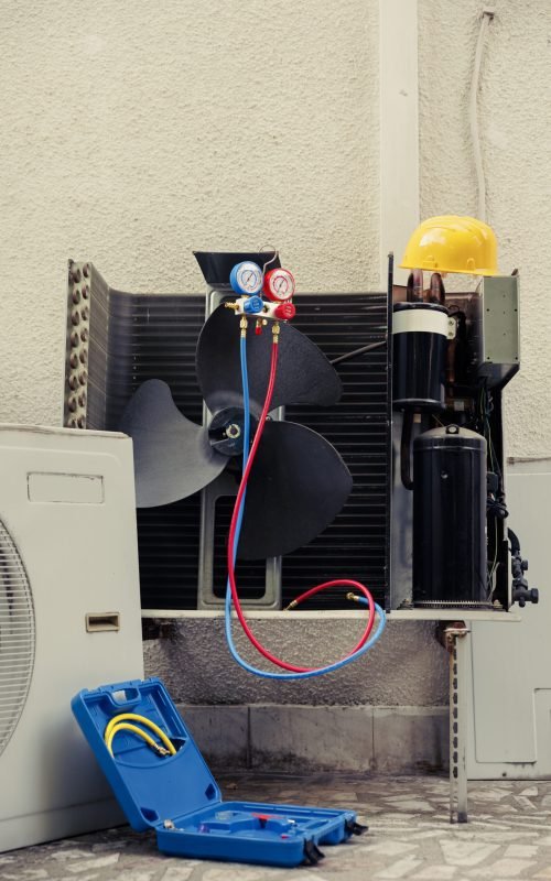 Faulty outdoor air conditioner system with protection cover removed in need of mending, with defective electric internal parts. External HVAC system not functioning anymore, ready to be repaired